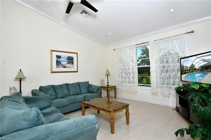 Living room with ceiling fan, ornamental molding, light tile patterned floors, recessed lighting, and vaulted ceiling