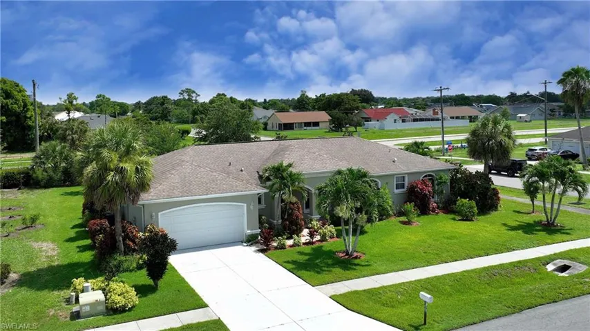 Ranch-style home with an attached garage, driveway, a residential view, a front lawn, and stucco siding