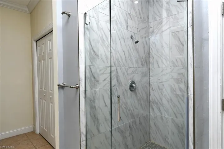 Full bath with crown molding, a shower stall, and tile patterned floors