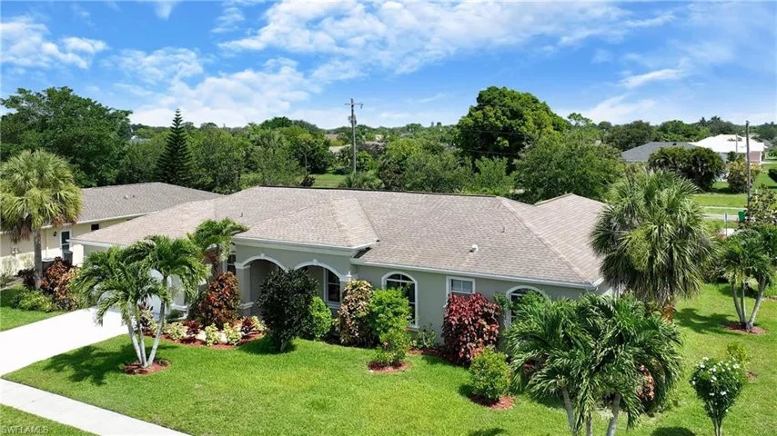 View of front of home featuring a front lawn, stucco siding, driveway, and a shingled roof