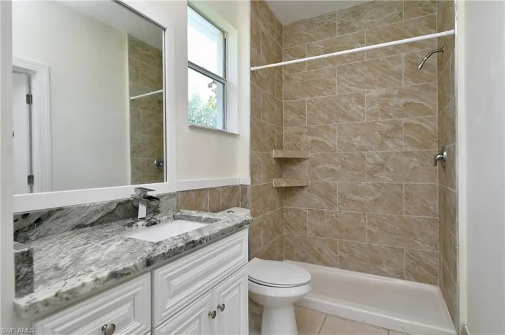 Bathroom featuring vanity, a tile shower, and tile patterned floors