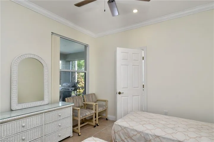Bedroom with ornamental molding, light tile patterned floors, and ceiling fan