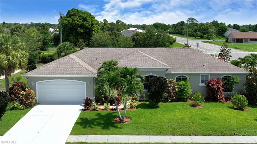 Single story home featuring a garage, a front lawn, stucco siding, driveway, and a shingled roof