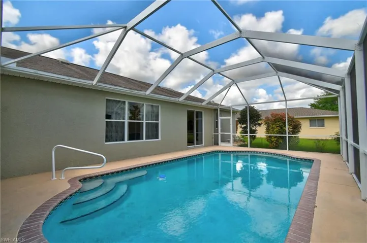 Swimming pool with a patio and glass enclosure