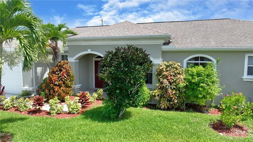 View of front of home with a shingled roof, a front yard, and stucco siding