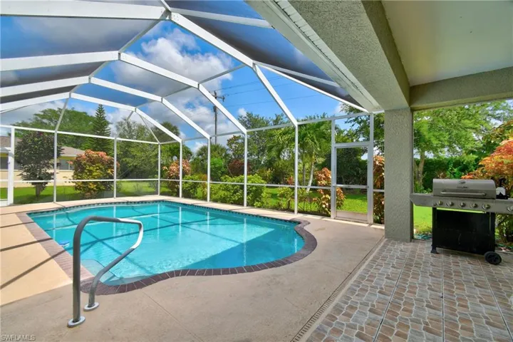 Swimming pool featuring a patio area, area for grilling, and glass enclosure