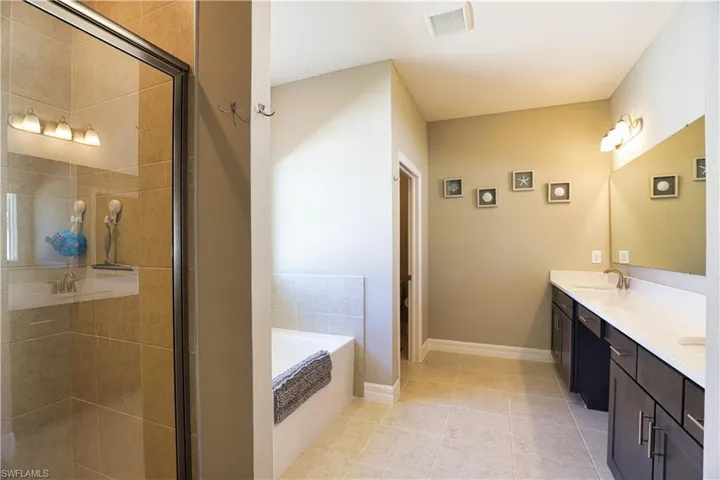 Full bath with a bath, double vanity, a stall shower, and tile patterned floors