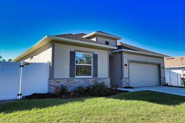 Prairie-style house with stone siding, a garage, concrete driveway, and stucco siding