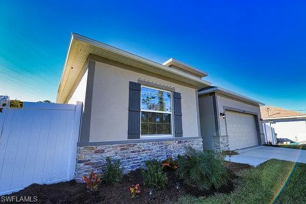 View of property exterior with stucco siding, stone siding, an attached garage, and driveway