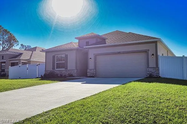 View of front of home with stone siding, stucco siding, an attached garage, and driveway