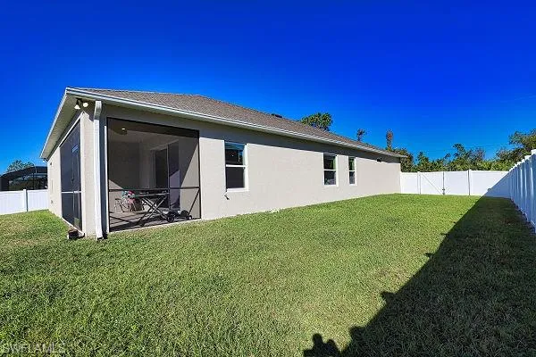 Back of house featuring a fenced backyard, stucco siding, and a sunroom