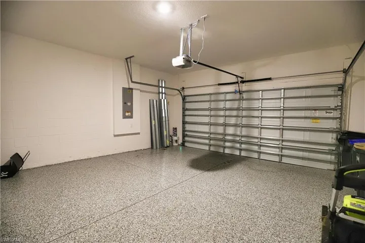 Garage featuring a garage door opener, electric panel, and concrete block wall