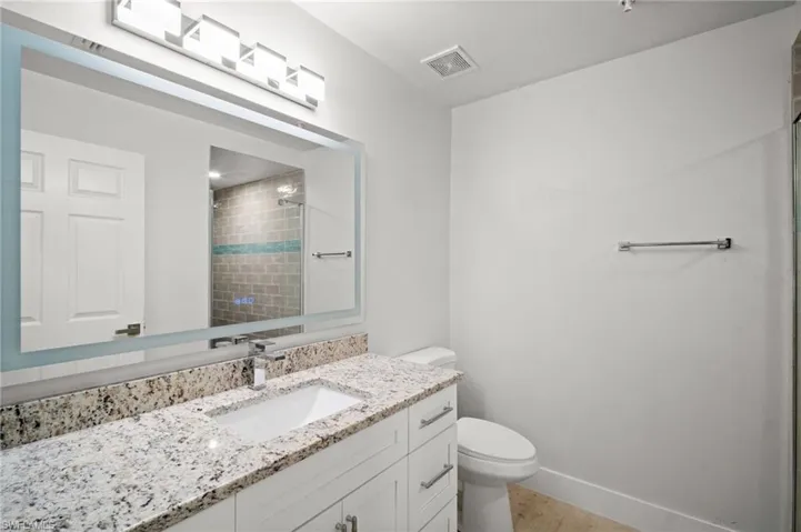 Bathroom with vanity, a tile shower, and light wood-style floors