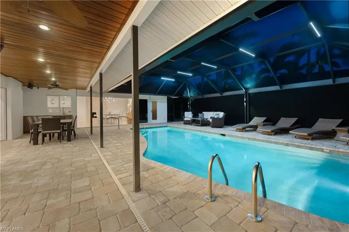Pool at twilight featuring an outdoor living space, a patio, an indoor pool, outdoor dining space, and ceiling fan
