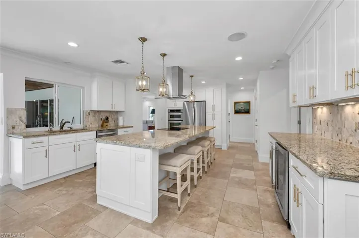 Kitchen featuring decorative backsplash, white cabinetry, a breakfast bar area, pendant lighting, and recessed lighting