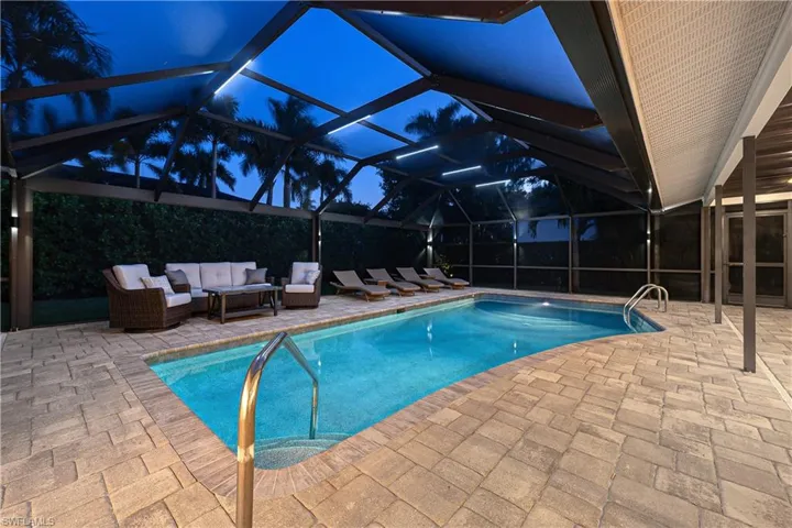 Outdoor pool featuring glass enclosure, a patio area, and a sunroom