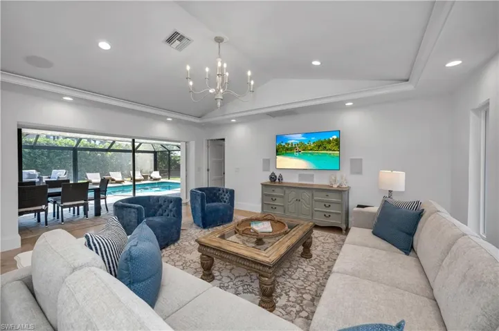 Living area featuring vaulted ceiling, a sunroom, recessed lighting, and a chandelier