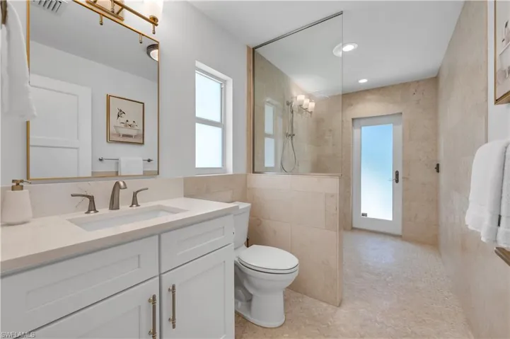 Full bath with vanity, tile walls, recessed lighting, tiled shower, and light tile patterned flooring