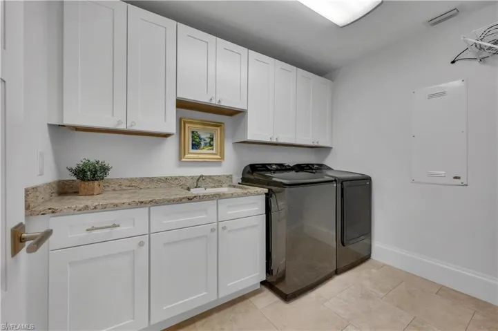 Laundry area with cabinet space, washing machine and dryer, and light tile patterned floors