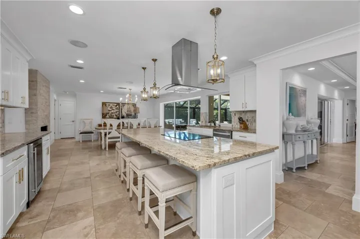 Kitchen featuring tasteful backsplash, hanging light fixtures, light stone counters, a kitchen island, and a breakfast bar area