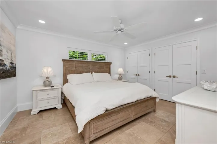 Bedroom with two closets, ornamental molding, ceiling fan, and recessed lighting