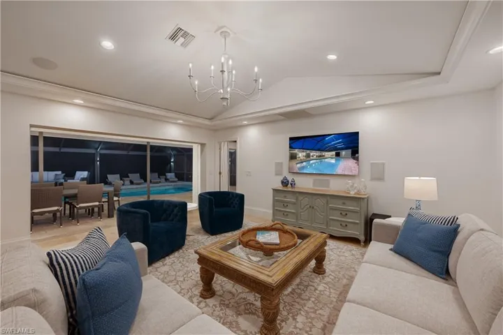 Living room with vaulted ceiling, recessed lighting, light wood-style floors, and a chandelier