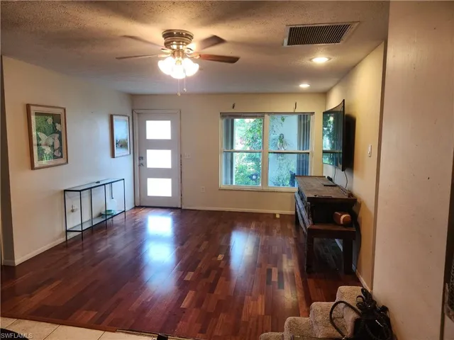 Foyer with wood finished floors, ceiling fan, and a textured ceiling