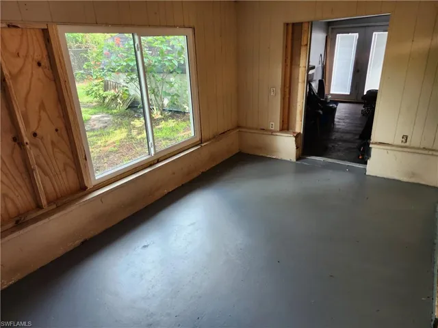 Empty room with finished concrete floors, plenty of natural light, wooden walls, and french doors