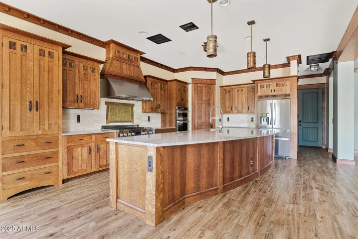 Custom cabinetry, stainless appliances, and a sprawling granite island define this gourmet kitchen, blending functionality with timeless Arts & Crafts elegance in Desert Ridge.