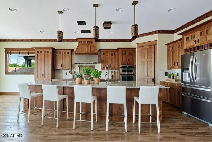 The gourmet kitchen includes a Jenn-Air gas range, double ovens, and a granite-topped island perfect for cooking, serving, or gathering. Beautiful custom cabinetry completes the scene.