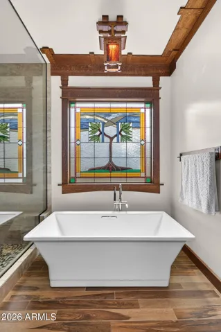 Enjoy a spa-like experience in this Phoenix home's elegant bathroom featuring a freestanding soaking tub beneath a stunning stained glass window. The combination of timeless design and natural light creates a serene retreat within this updated, energy-efficient property.