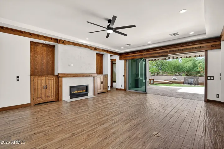This beautifully designed living space features custom Stickley-style oak cabinetry, a gas fireplace with artisan stonework, and vintage lighting, offering warmth and character throughout the heart of the home.