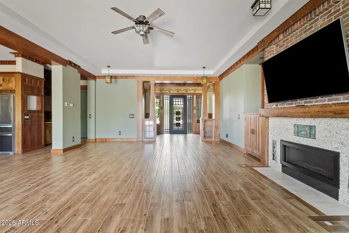 The open-concept living area features hardwood-look porcelain tile, decorative beams, and Craftsman-era lighting. Abundant natural light enhances the Arizona indoor-outdoor lifestyle.