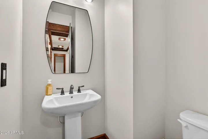 The powder room makes a statement with a craftsman-style framed mirror, pedestal sink, and custom lighting. Ideal for guests and beautifully aligned with the home's Arts & Crafts aesthetic.