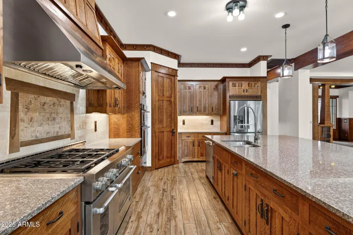 Jenn-Air Pro appliances, a statement range hood, and artisan backsplash highlight this chef’s kitchen. Designed for performance and beauty in this Phoenix dream home.