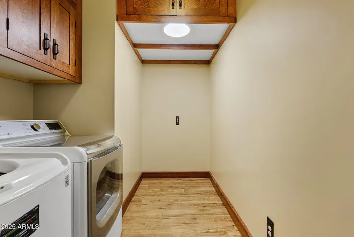 This laundry space offers practicality with upper custom oak cabinets, modern appliances, and a wood-look tile floor—blending design and utility for everyday living in Phoenix.