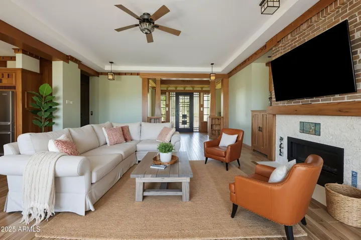 The open-concept living area features hardwood-look porcelain tile, decorative beams, and Craftsman-era lighting. Abundant natural light enhances the Arizona indoor-outdoor lifestyle.