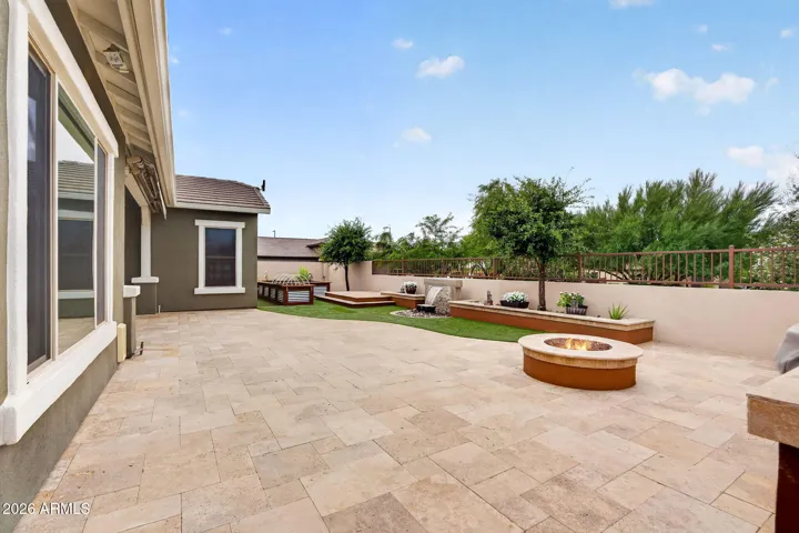The backyard showcases a stylish firepit, garden planters, and ample seating space. A perfect fusion of indoor-outdoor living in this updated, energy-efficient Phoenix property.