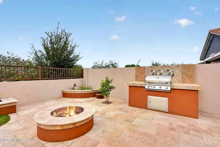 Entertain with ease on this expansive backyard patio, complete with a built-in BBQ, dining area, and built-in bench seating. The low-maintenance landscape and firepit offer Arizona outdoor living at its best.