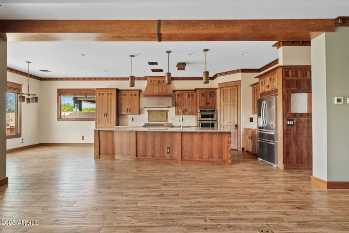 Custom millwork and rich wood tones define this spacious kitchen, paired with granite countertops and stainless appliances. A perfect blend of artistry and functionality in the heart of the home.