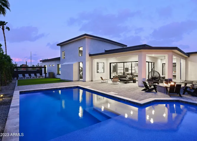 Stunning private yard with sparkling pool, sun loungers, lawn space, covered patio with lounge area, covered outdoor dining area, fire pit, and built-in BBQ grill!
