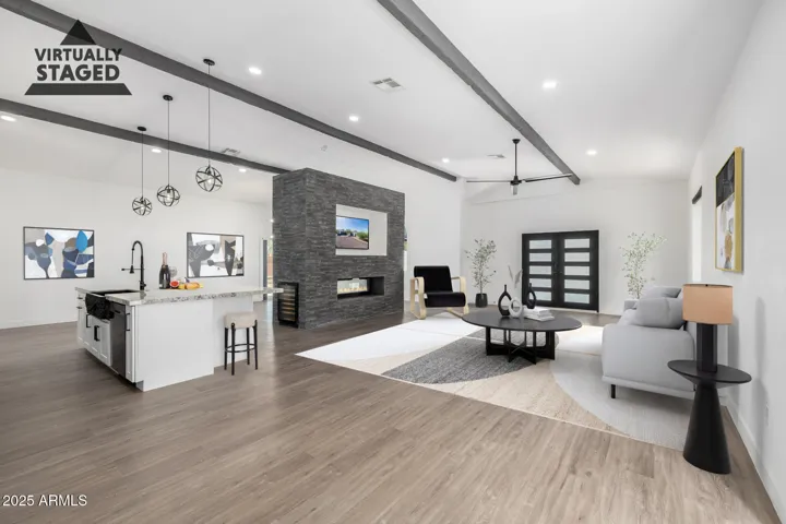 This space is versatile and generous! Vaulted ceilings lead you past the two way fire place into the first great room with the kitchen and laundry area beyond the barn door in the distance. Behind the island fireplace is an additional great room that can be utilized as a office, formal dining, or second living space.