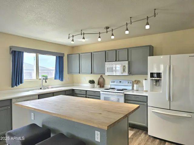 Bright kitchen with gray cabinets and butcher block island.
