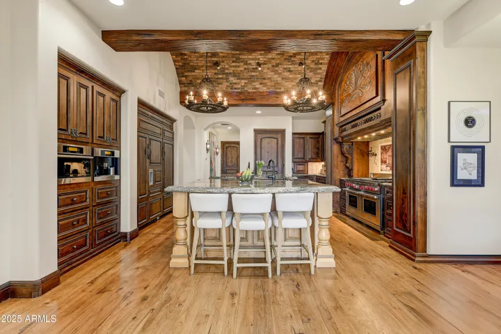 Granite-topped island with seating for four, anchored beneath a soaring ceiling and surrounded by high-end appliances. This kitchen is designed for both daily living and upscale entertaining.
