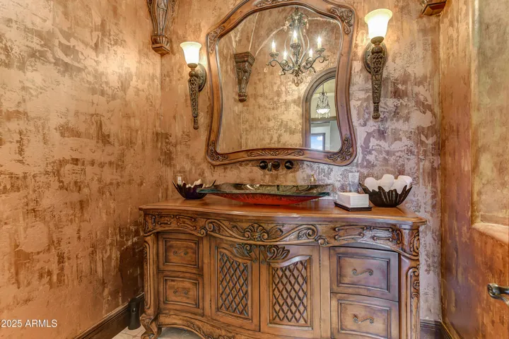 This Scottsdale home’s powder room is a true work of art. Featuring a carved antique vanity, rich copper vessel sink, and ornate sconces, it combines Tuscan charm with luxurious finishes that impress guests and enhance everyday comfort.