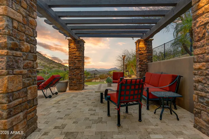 Relax beneath this elegant covered patio framed with stone pillars and a wood pergola. With comfortable seating and open desert views, it’s the perfect spot to unwind or entertain in the cool evening breeze.