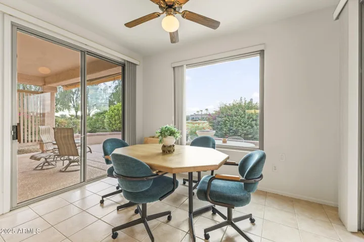 Charming breakfast nook surrounded by large windows and patio access, offering peaceful golf course and garden views for morning coffee or casual dining.
