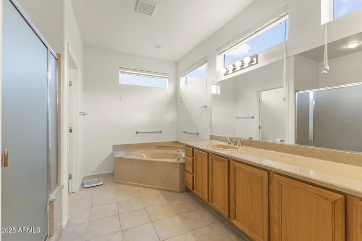 Spacious primary bathroom featuring a large soaking tub, dual vanities, and bright transom windows for natural light and privacy.