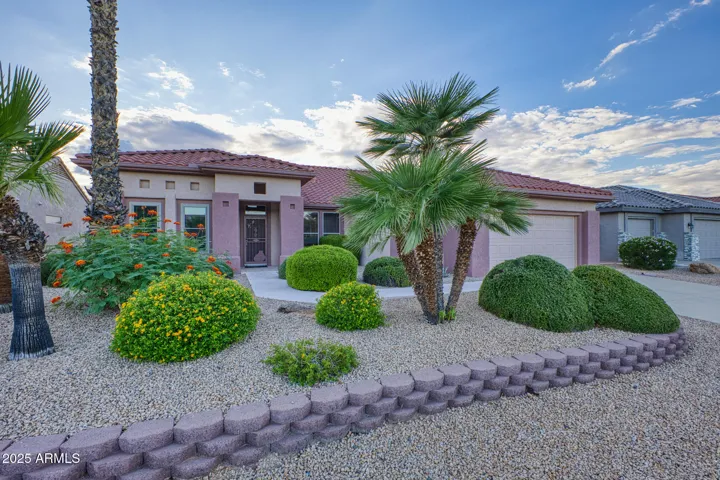 Beautifully landscaped front yard with low-maintenance desert plants, mature palms, and flowering shrubs enhancing the home’s curb appeal.