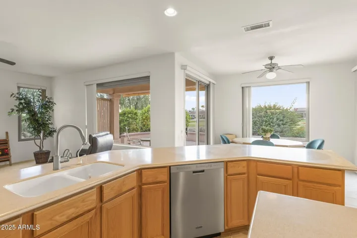 Spacious kitchen featuring stainless appliances, wraparound counters, and views of the lush backyard and golf course beyond—perfect for indoor-outdoor living.